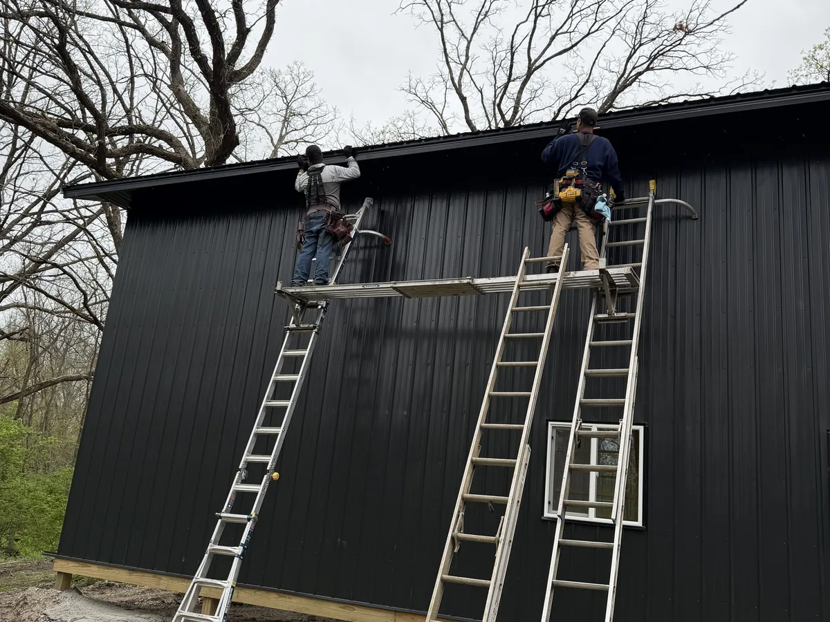 Crew installing black metal board-and-batten siding