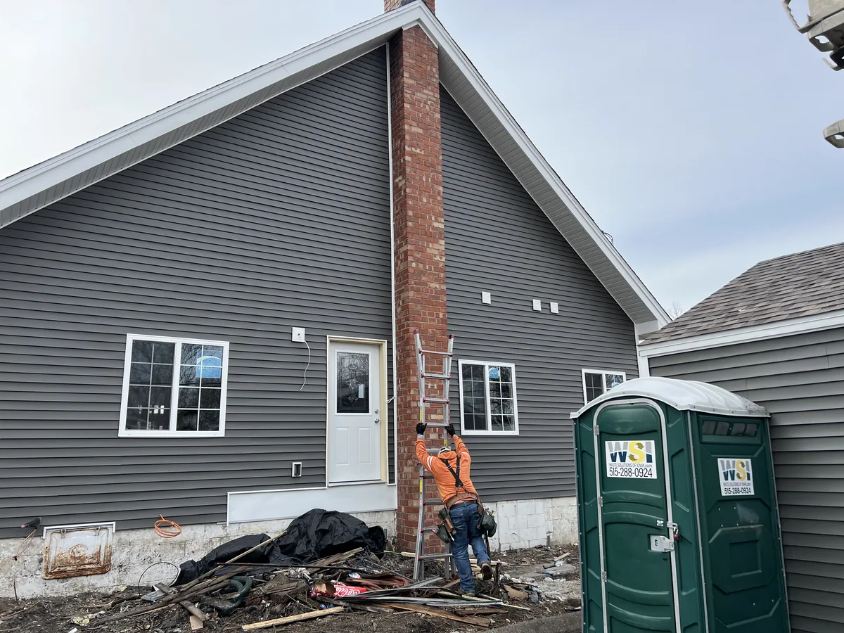 Gray siding and new white windows beside a brick chimney