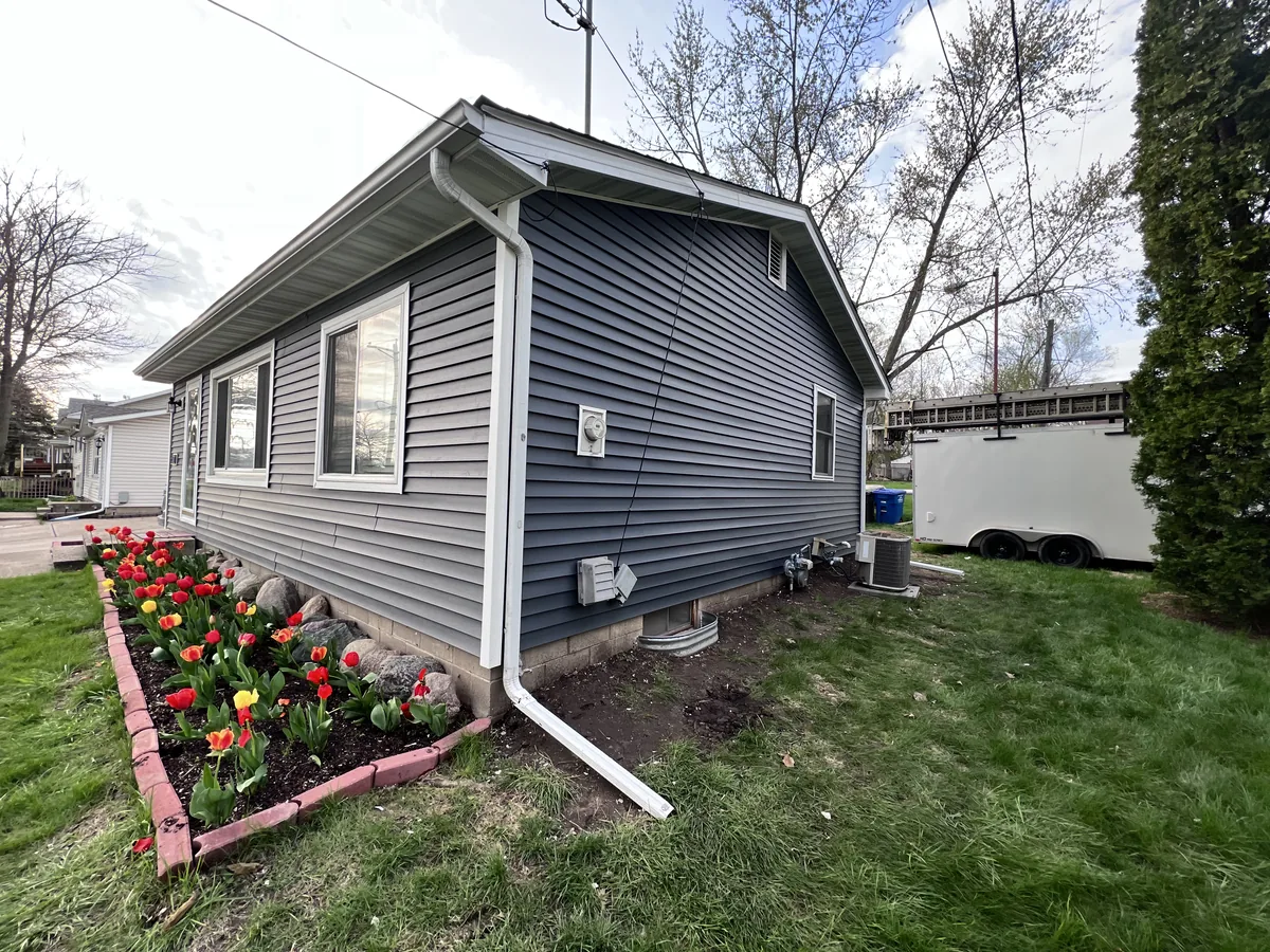 Gray vinyl siding with white downspout on a ranch home