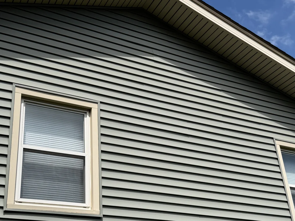 Close-up of tan vinyl siding and white window wrap